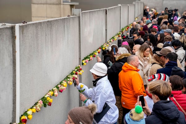 People attend a flower laying ceremony on occasion of the 35th wall anniversary at the grounds of the Berlin Wall Memorial, Berlin, Germany, Saturday, Nov.9, 2024. (AP Photo/Ebrahim Noroozi)