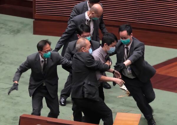 Pro-democracy lawmaker Ted Hui, center, struggles with security personnel at the main chamber of the Legislative Council during the second day of debate on a bill that would criminalize insulting or abusing the Chinese anthem in Hong Kong.