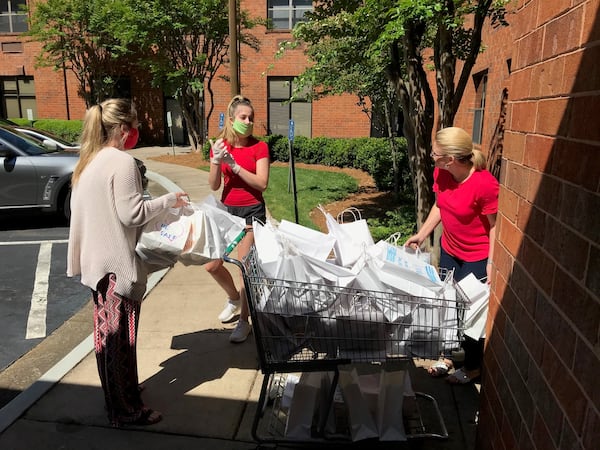 Avery Pursell (center) delivers gifts bags to Rita Malone (right), assistant executive director at Mount Vernon Towers Condominiums, with assistance from staffer Taylor Williams (left.) Pursell and her colleagues collected 300 books of large-print crossword puzzles and other amusements to distribute to the residents at the senior living center. BO EMERSON/BEMERSON@AJC.COM