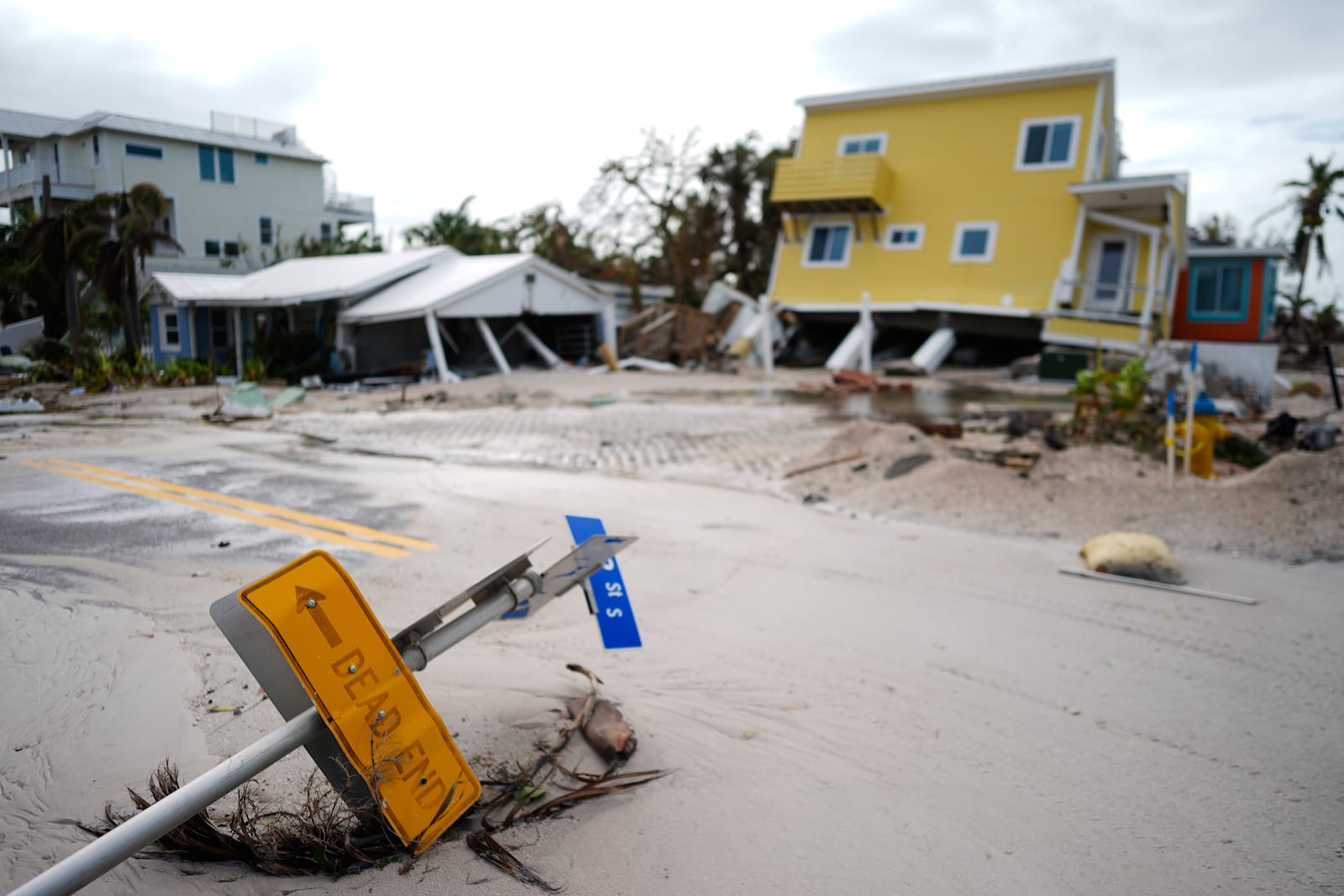 FILE - A house sits toppled off its stilts after the passage of Hurricane Milton, alongside an empty lot where a home was swept away by Hurricane Helene, in Bradenton Beach on Anna Maria Island, Fla., Oct. 10, 2024. (AP Photo/Rebecca Blackwell, File)