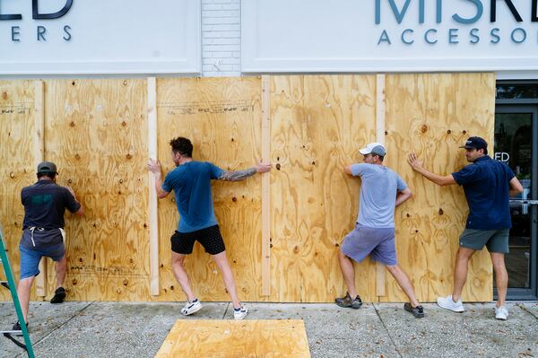 Workers board up a shopfront on Central Ave in St. Petersburg, Fla. in anticipation of Hurricane Ian on Sept. 27, 2022. Preparations have begun in Florida, where a combination of dangerous storm surges, flooding and powerful winds are expected in the coming days. (Bob Croslin/The New York Times)