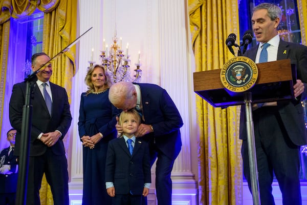 President Joe Biden kisses his grandson Beau Biden, while joined by second gentleman Doug Emhoff (left), first lady Jill Biden and Rabbi Elliott Cosgrove (right) during a Hanukkah event at the White House on Monday. Hanukkah begins at sundown on Wednesday.