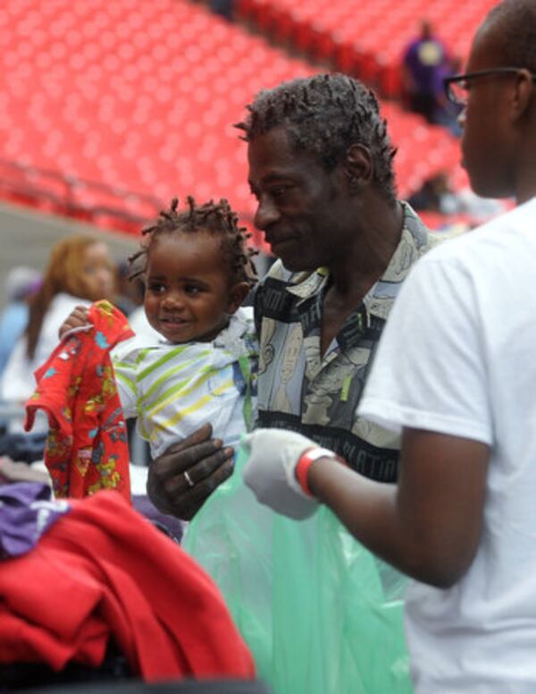 James McClure (center) picks up some new clothes for his son Jimmy, 16 months, with the help of volunteer Tyeshaun Brinson (right). (AJC file photo / Bita Honarvar)