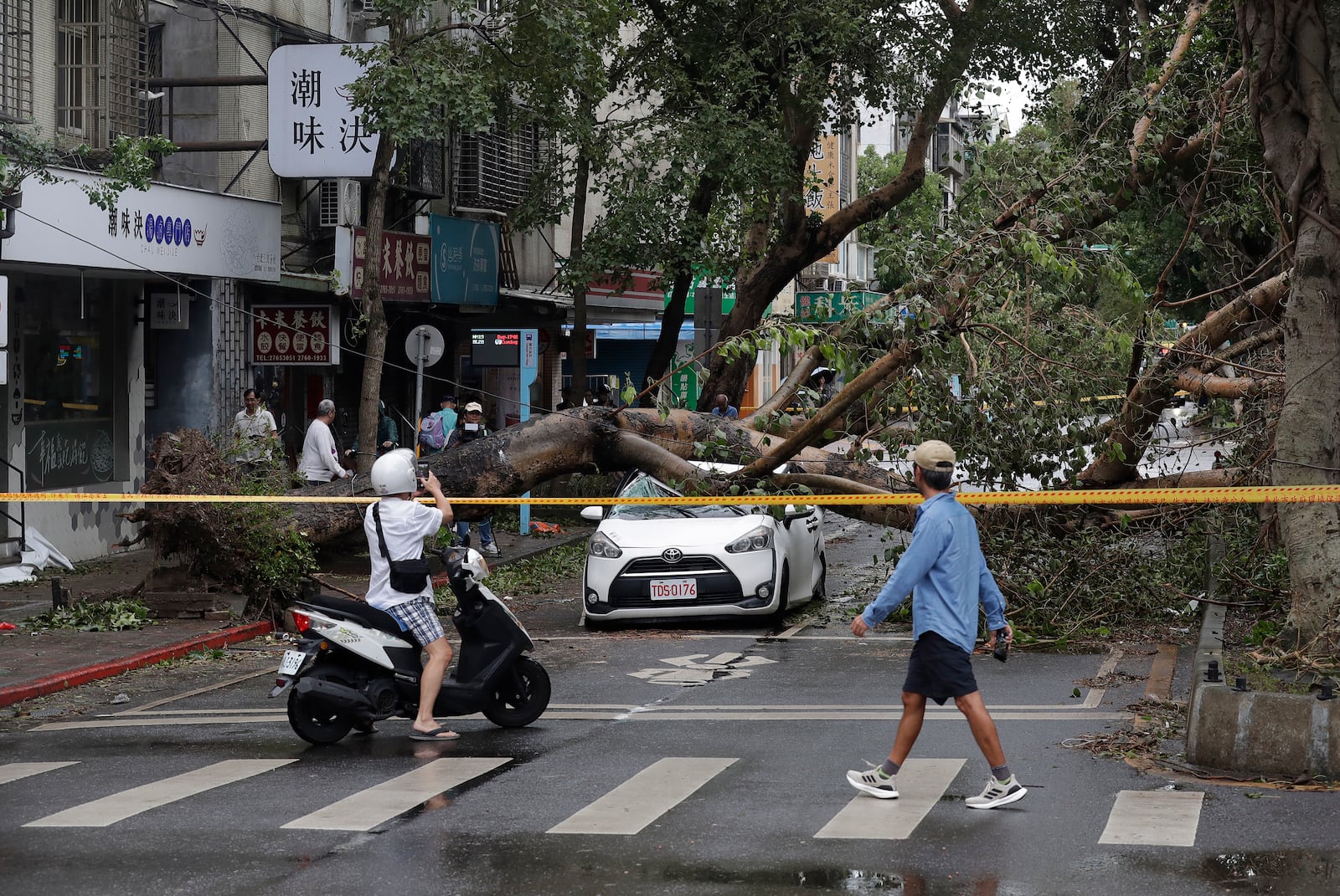 People walk past an area destroyed by the wind from Typhoon Kong-rey in Taipei, Taiwan, Friday, Nov. 1, 2024. (AP Photo/Chiang Ying-ying)