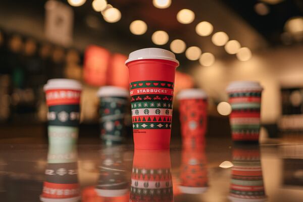 Customers can get a free red Starbucks holiday cup with a red sweater design, pictured in front, when they order select drinks for the 2020 holiday season.