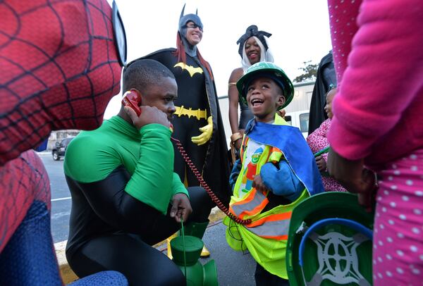 Here’s "Super DJ," DJ Pitts, then 4, reacting as Dru Phillips (Green Lantern) amuses him after DJ pushed the button to implode the 19-story former Executive Park Motor building at the corner of I-85 and North Druid Hills Road on Saturday morning, November 8, 2014.  HYOSUB SHIN / HSHIN@AJC.COM