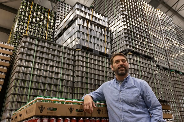 Jeff Ware, president of Resurgence Brewing Company, poses for a portrait near a stockpile of aluminum cans, which are sourced from Canada, Thursday, Feb. 27, 2025, in Buffalo, N.Y. (AP Photo/Lauren Petracca)