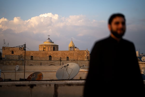 An Armenian Christian deacon walks on a roof terrace near St. James Cathedral, background, at the Armenian quarter in Jerusalem, Thursday, Nov. 21, 2024. (AP Photo/Francisco Seco)