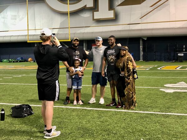 Hillgrove offensive lineman Ben Galloway (second from right) and Georgia Tech offensive line coach Brent Key (third from right) take a photo after Galloway received a scholarship offer from Key following a Tech prospect camp June 9, 2022. With Galloway are his father Kenya, his mother Nadia and his sister Nola. Tech graduate assistant Nathan Brock is taking the photo. (AJC photo by Ken Sugiura)