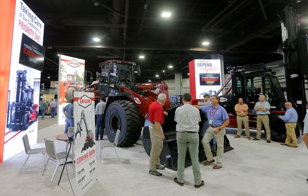 Exhibitors and attendees mingle at the Taylor Machine Works, Inc. booth during the Forest Products Machinery & Equipment Expo in the Georgia World Congress Center in Atlanta on Wednesday. The exposition featured equipment manufacturers in the wood processing industry. Due to COVID-19, attendees are required to complete a health survey before entering the convention. Masks are optional. (Christine Tannous / christine.tannous@ajc.com)