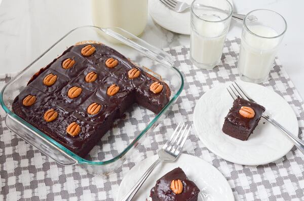 Dark and rich Gluten-Free Chocolate Snack Cake is shown here topped with optional pecans and served with milk. 
(Virginia Willis for The Atlanta Journal-Constitution)