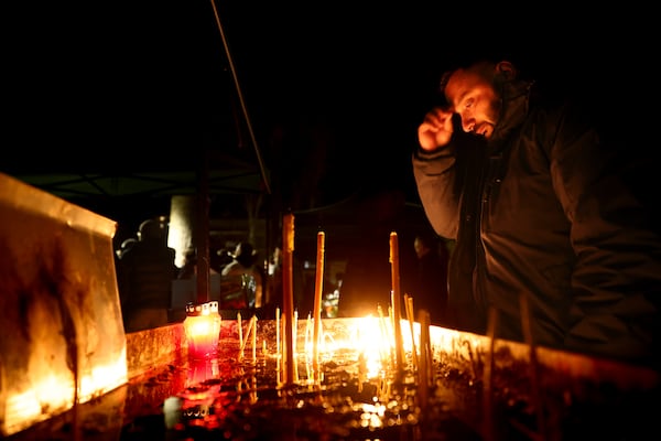 A man lights candles during a vigil in the town of Kocani, North Macedonia, Tuesday, March 18, 2025 following a massive fire in a nightclub early Sunday. (AP Photo/Armin Durgut)