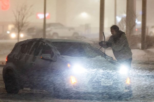 A motorist adjusts their windshield wipers near Saddle Creek Road and Leavenworth Street during a blizzard warning in Omaha, Neb., Tuesday, March 4, 2025. (Chris Machian/Omaha World-Herald via AP)