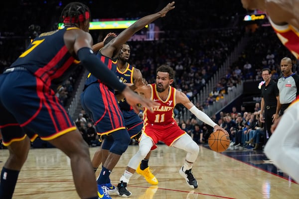 Atlanta Hawks guard Trae Young (11) looks for an open teammate while defended by Golden State Warriors forwards Draymond Green, second from left, and Andrew Wiggins during the first half of an NBA basketball game Wednesday, Nov. 20, 2024, in San Francisco. (AP Photo/Godofredo A. Vásquez)