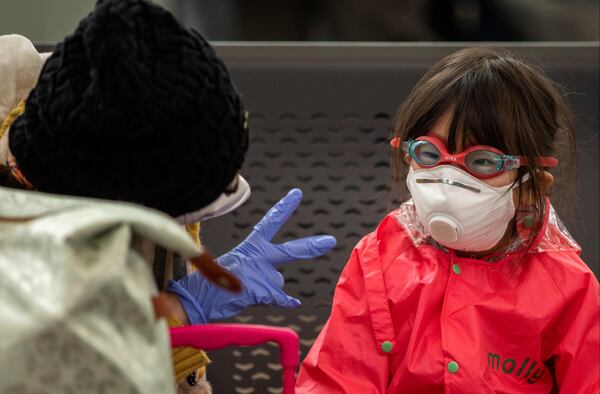 A woman plays with her daughter as they wait at Barcelona airport, Spain, Saturday, March 14, 2020. Spain's prime minister has announced a two-week state of emergency from Saturday in a bid to contain the new coronavirus outbreak. For most people, the new coronavirus causes only mild or moderate symptoms. For some, it can cause more severe illness, especially in older adults and people with existing health problems. (AP Photo/Emilio Morenatti)