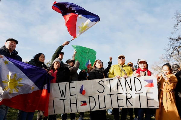 Supporters of former Philippine President Rodrigo Duterte wave a flag and banner during a demonstration outside the International Criminal Court detention center near The Hague in Scheveningen, Netherlands, Wednesday, March 12, 2025. (AP Photo/Omar Havana)