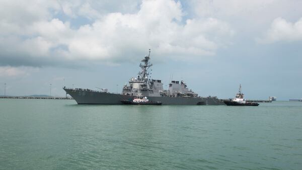 CHANGI NAVAL BASE, SINGAPORE:  In this released U.S. Navy handout, tugboats from Singapore assist the Guided-missile destroyer USS John S. McCain (DDG 56) at it steers towards Changi Naval Base, Republic of Singapore following a collision with the merchant vessel Alnic MC while underway east of the Straits of Malacca and Singapore on Aug. 21. Significant damage to the hull resulted in flooding to nearby compartments, including crew berthing, machinery, and communications rooms. Damage control efforts by the crew halted further flooding. The incident will be investigated.