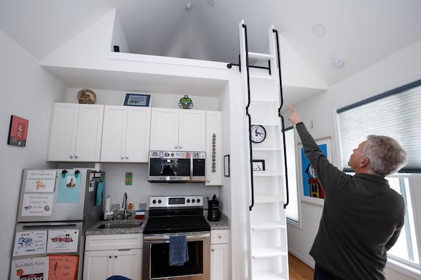 Rich Pasenow points to the storage area inside of his tiny home in Clarkston on Tuesday, Feb. 27, 2024. In 2019, DeKalb County approved the tiny home and cottage neighborhood that consists of eight homes that sit on half an acre. (Natrice Miller/ Natrice.miller@ajc.com)