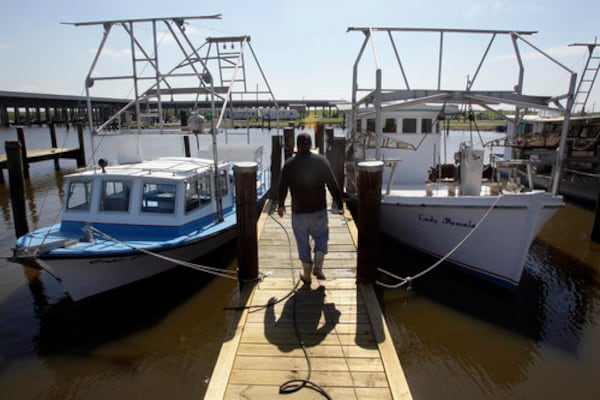 In this March 31, 2011 photo, commercial fisherman Stanley Encalade walks down a dock toward a pair of his family's boats while doing maintenance work at a marina in Pointe A La Hache, La. Encalade, who stays busy by fixing up his boats while he waits for oyster season to open, had his oyster beds impacted by oil and freshwater diversion projects that attempted to keep oil away from the coast.