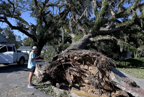 Valdosta State University student Nealy Hiers takes a picture of a fallen tree caused by Hurricane Helene. The storm ripped through the state, killing at least 25 Georgians. (Hyosub Shin/AJC)