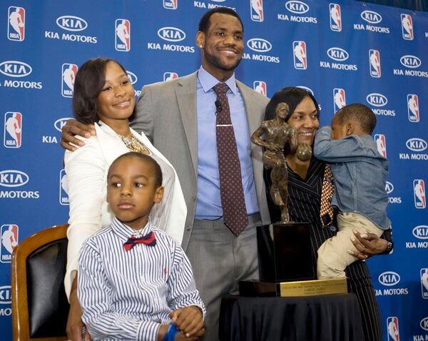 FILE - Cleveland Cavaliers forward and NBA Most Valuable Player LeBron James, center, stands with his family, girfriend, Savannah Brinson, left, in white, son, LeBron Jr., foreground left, James mother Gloria, right, holding James son Bryce, after the NBA MVP award ceremony for James on the University of Akron campus in Akron, Ohio, Sunday, May 2, 2010. (AP Photo/Phil Long, File)