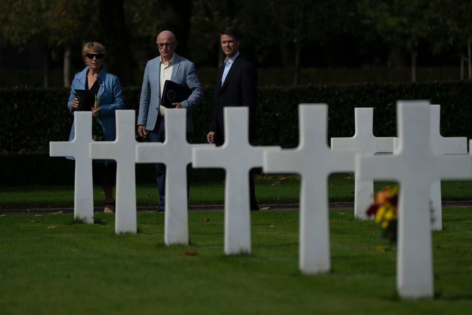 Eighty years after the liberation of the south of the Netherlands, Scott Taylor, right, Ton Hermes, center, and Maria Kleijnen, left, walk to the grave of Scott's grandfather Second Lt. Royce Taylor, a bombardier with the 527 Bomb Squadron, at the Netherlands American Cemetery in Margraten, southern Netherlands, on Wednesday, Sept. 11, 2024. (AP Photo/Peter Dejong)