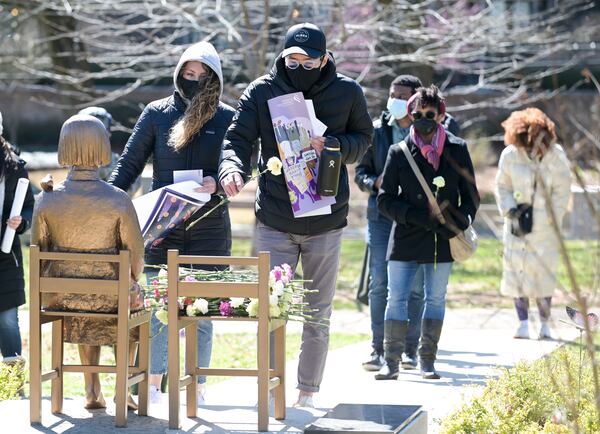 Laura DeGroot (left) and Robert Sakamaki lay flowers on a statue during an event paying tribute to the victims of the Atlanta spa shootings Saturday, March 12, 2022. (Photo: Daniel Varnado for the Atlanta Journal-Constitution)