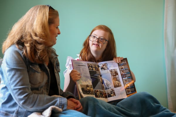 Darden Glass shows her mother Betsy Glass a page in her high school’s yearbook. Darden takes special education classes at her local high school and will likely graduate in the next couple of years. (Jason Getz / Jason.Getz@ajc.com)