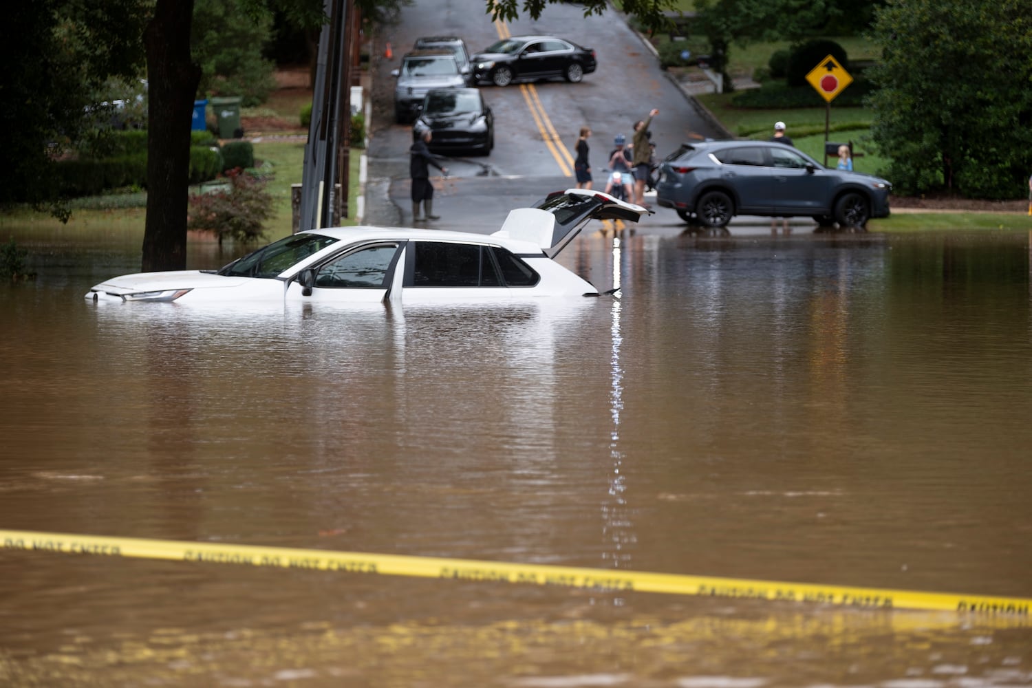 A partially submerged car sits on Sagamore Drive after Peachtree Creek spills over its banks in Atlanta on Friday, Sept. 27, 2024 following a night of heavy rain from Hurricane Helene.ÊÊÊBen Gray for the Atlanta Journal-Constitution