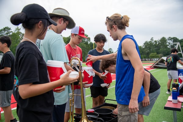 The drum majors serve ice to their band mates Wednesday, July 26, 2023, to help keep them on their toes during practice at North Gwinnett HS. (Jamie Spaar for the Atlanta Journal-Constitution)