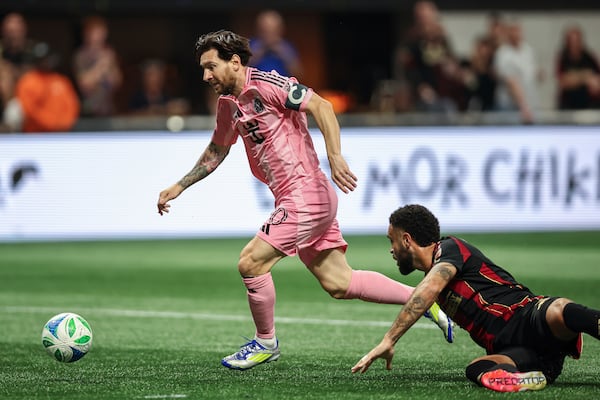 Inter Miami forward Lionel Messi, left, dribbles past Atlanta United defender Derrick Williams, right, before scoring in the first half of an MLS soccer match Sunday, March, 16, 2025, in Atlanta. (AP Photo/Colin Hubbard)