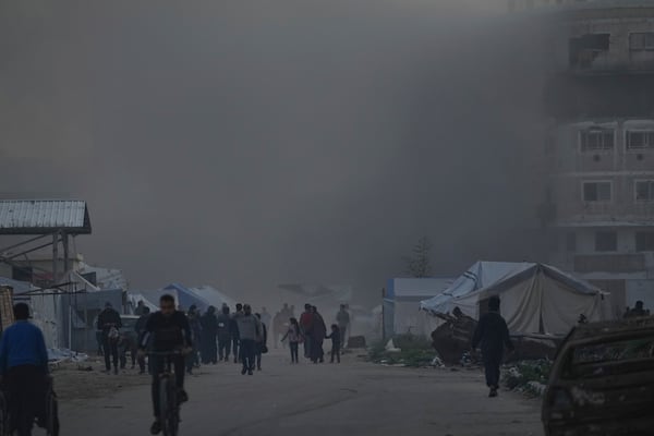 Surrounded by smoke from a nearby Israeli army strike, Palestinians walk past tents in central Gaza City on Saturday, March 22, 2025. (AP Photo/Jehad Alshrafi)