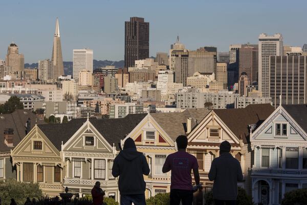 The silhouettes of pedestrians stand in front of Victorian homes and the downtown skyline in San Francisco, where the median home price is more than twice that of Atlanta. (David Paul Morris/Bloomberg)