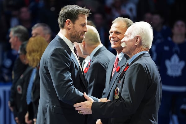 2024 Hockey Hall of Fame inductee Shea Weber, left, shakes hands with Lanny McDonald, right, as Mike Gartner, center, looks on during a ceremony prior to NHL hockey game action between the Detroit Red Wings and the Toronto Maple Leafs in Toronto, Friday, Nov. 8, 2024. (Frank Gunn/The Canadian Press via AP)