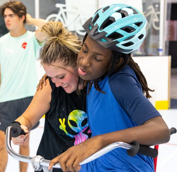 Volunteers Heather Genzale got a hug from special needs camper, Ezekiel, while he learned how to ride a two-wheel bike without adaptations. PHIL SKINNER FOR THE ATLANTA JOURNAL-CONSTITUTION.