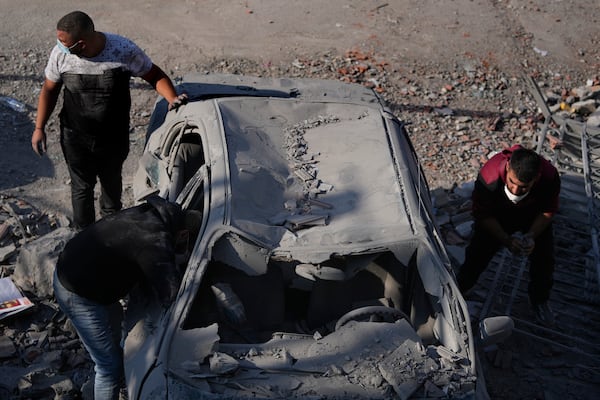 People check a damaged car at the site where an Israeli airstrike hit a house in Aalmat village, northern Lebanon, Sunday, Nov. 10, 2024. (AP Photo/Hassan Ammar)