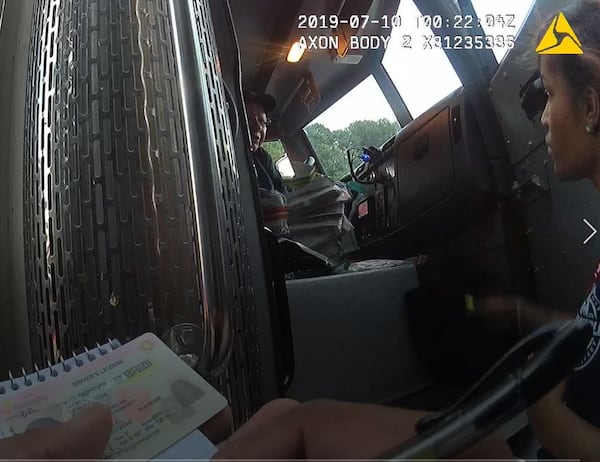 A Dunwoody police officer speaks with the drivers of the GardaWorld armored truck that spilled an estimated $175,000 onto I-285 on July 9. DUNWOODY POLICE DEPARTMENT