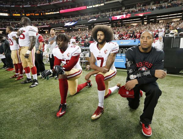 In this Dec. 18, 2016, file photo, San Francisco 49ers quarterback Colin Kaepernick (7) and outside linebacker Eli Harold (58) kneel during the playing of the national anthem before an NFL football game against the Atlanta Falcons in Atlanta. (AP Photo/John Bazemore, File)