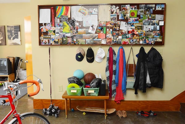 Ryan Gravel created the corkboard that is filled with photos of family and friends. Dog leashes, scarves, purses and jackets hang from hooks, while baskets of sports equipment and a skateboard find their home here, too.