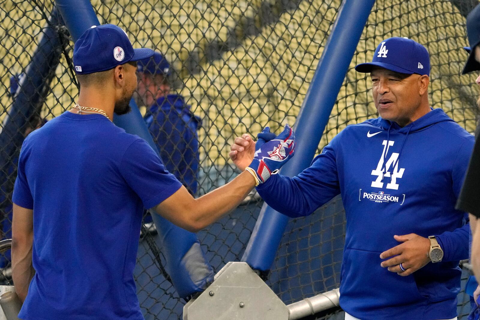 Los Angeles Dodgers' Mookie Betts, left, and manager Dave Roberts greet each other during practice in preparation for Game 1 of a baseball NL Championship Series against the New York Mets, Saturday, Oct. 12, 2024, in Los Angeles. (AP Photo/Mark J. Terrill)