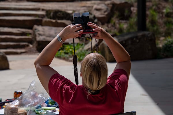 Bente Christensen looks through binoculars at the eclipsing sun. Her sister, a physics teacher, modified the binoculars for solar viewing. (Photo Courtesy of Lee Hedgepeth/Inside Climate News)