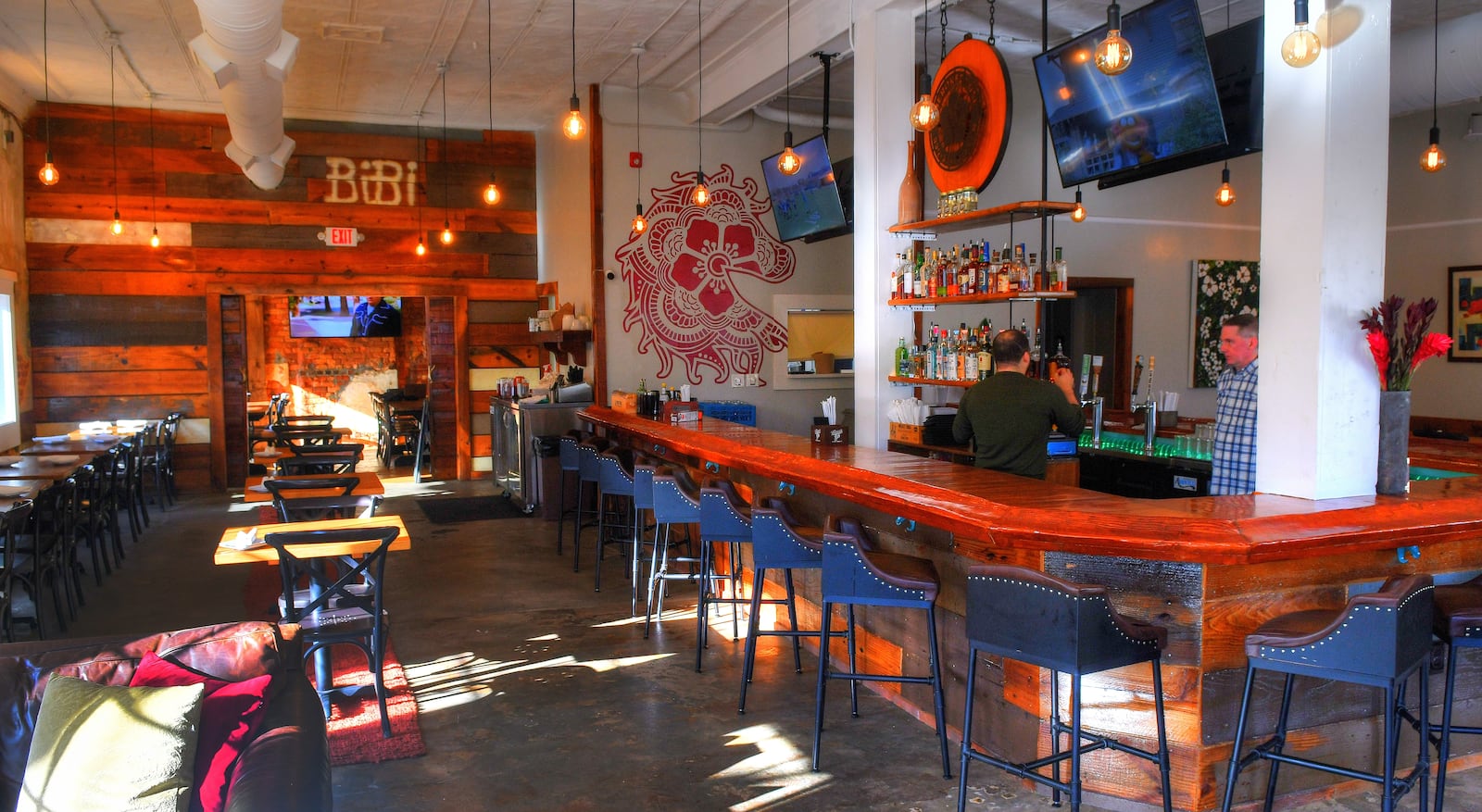 Bar and seating area at the Cherokee Rose BBQ Bar & Kitchen in Stone Mountain Village. In addition to separating the private dining area from the main, the large wooden sliding door (left) was repurposed from a South Georgia stable and has the names of past horses still marked on it. (Chris Hunt for The Atlanta Journal-Constitution)