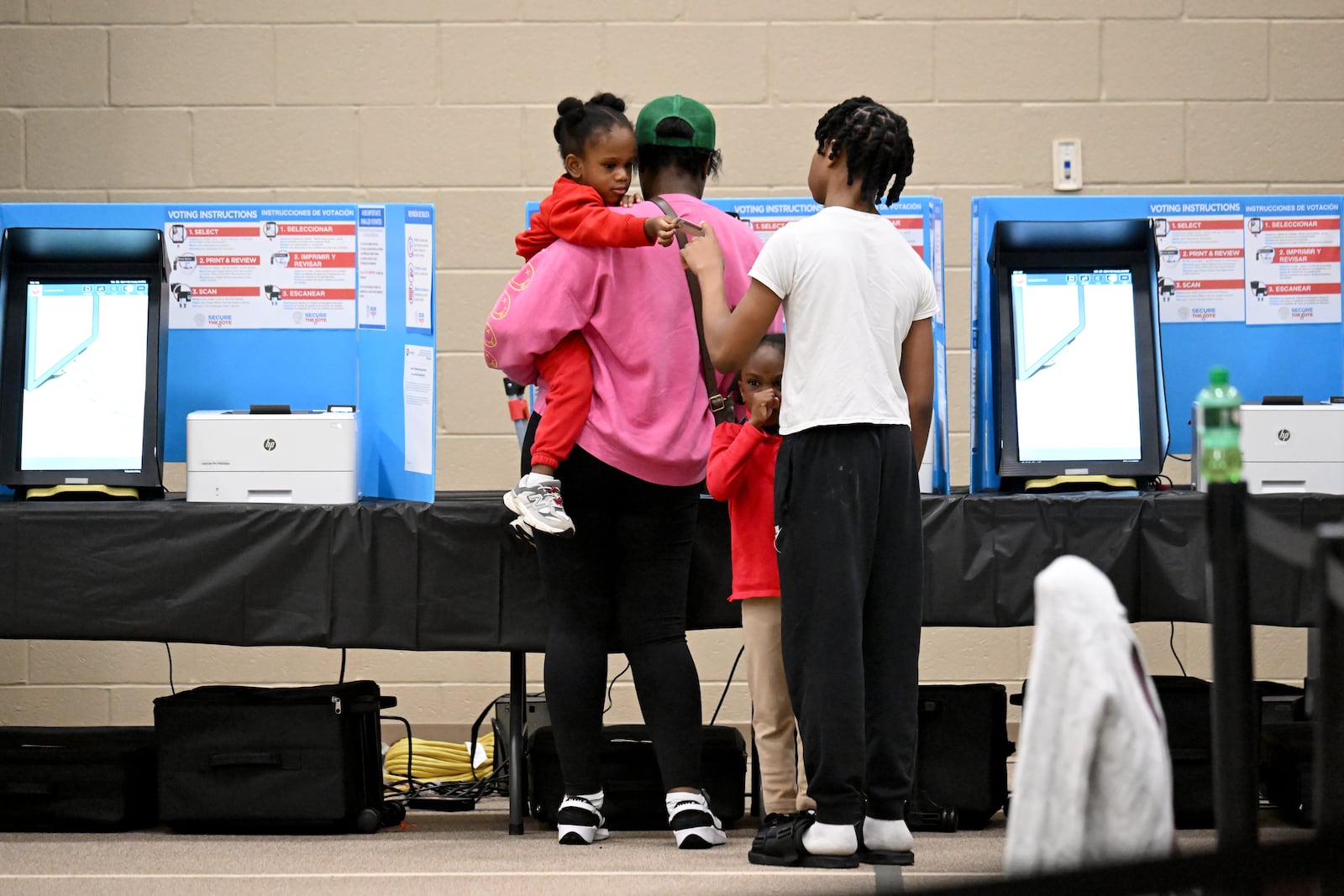 Erica Bryant holding her 2-year-old daughter Atiyah, 2, as she fills in her ballot while her other children are waiting on Election Day at Gracepointe Church of the Nazarene, Tuesday, November 5, 2024, in Loganville.(Hyosub Shin / AJC)