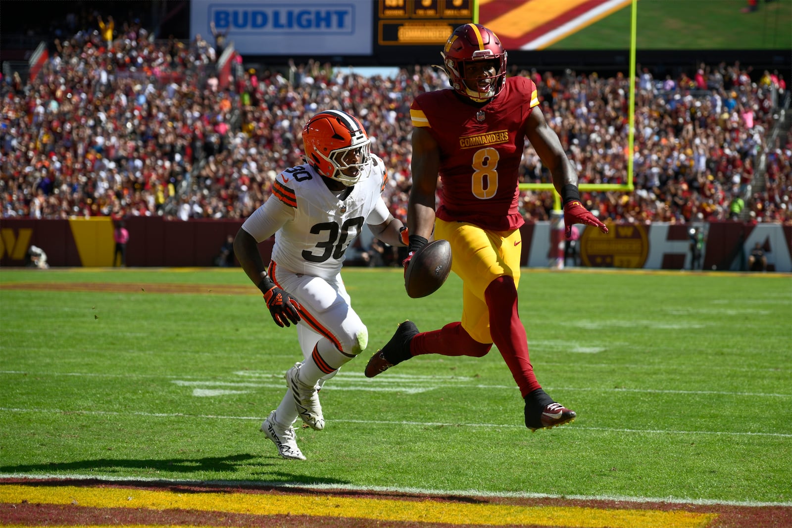 Washington Commanders running back Brian Robinson Jr. (8) runs into the end zone past Cleveland Browns linebacker Devin Bush (30) for a touchdown during the first half of an NFL football game in Landover, Md., Sunday, Oct. 6, 2024. (AP Photo/Nick Wass)