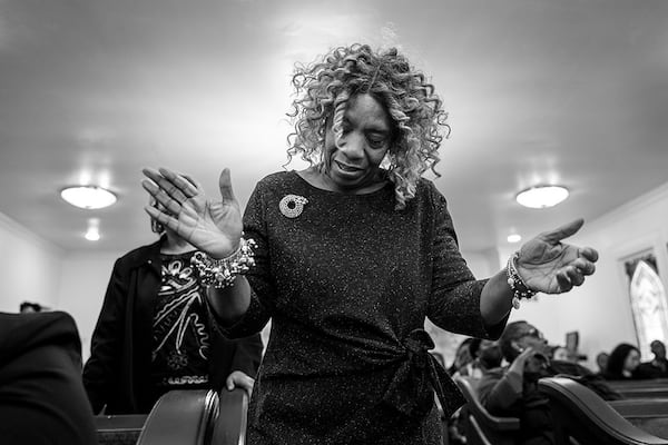 A mourner is swept up in gospel song during the homegoing of Marcus Johnson at Willie Watkins Funeral Home chapel on Nov. 11, 2023. (Arvin Temkar/AJC)