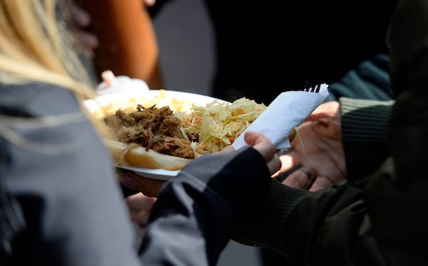 Marketing manager Fernanda Zedejas, left, hands a plate off at The Improper Pig's food truck, The Oinker, during lunch at the Salvation Army's Center of Hope in Charlotte, N.C., on March 14, 2017. (David T. Foster III/Charlotte Observer/TNS)