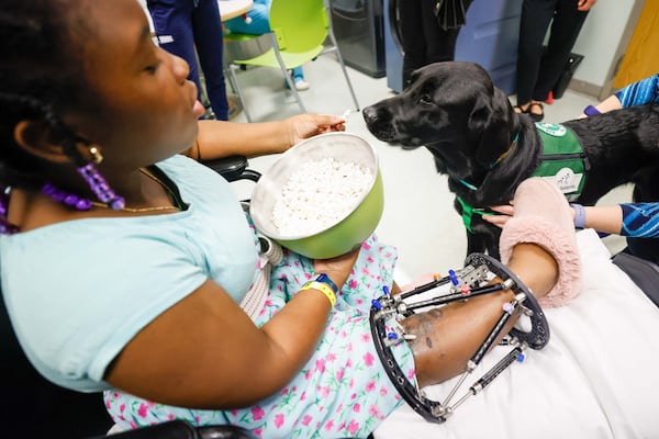 At the conclusion of her therapy session on Monday, Dec. 9, 2024, Emily Owie presents popcorn to Conway, the facility dog, at Children’s Healthcare of Atlanta’s Scottish Ritel. 
(Miguel Martinez / AJC)