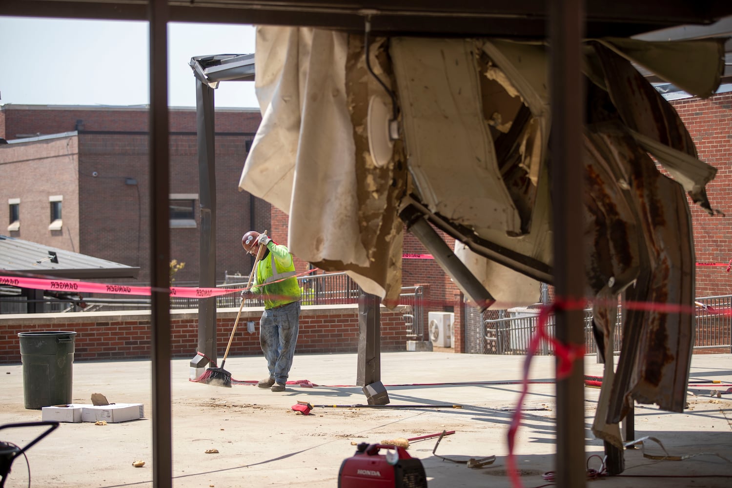 A workman sweeps up debris outside the damaged Newnan High School. (Alyssa Pointer / Alyssa.Pointer@ajc.com)