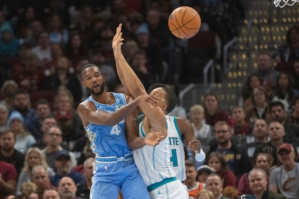 Cleveland Cavaliers' Evan Mobley (4) passes the ball as Charlotte Hornets' Grant Williams, front right, defends during the second half of an NBA basketball game in Cleveland, Sunday, Nov 17, 2024. (AP Photo/Phil Long)