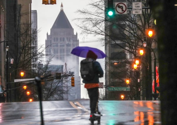 Scooting past Forsyth Street on Peachtree Street towards One Atlantic Center, this commuter chose a scooter and umbrella to travel in the rain as widespread rain fell across the region on Wednesday morning Jan. 27, 2021(John Spink / John.Spink@ajc.com)

